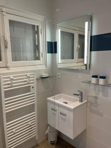 une salle de bain blanche avec un lavabo et un miroir dans l'établissement Maison de ville à la mer très bien équipée proche centre avec commerces, à Plouescat