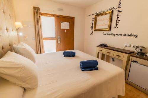 a bedroom with a white bed with two blue bags on it at Paloma Blanca Boutique Hotel in Marbella