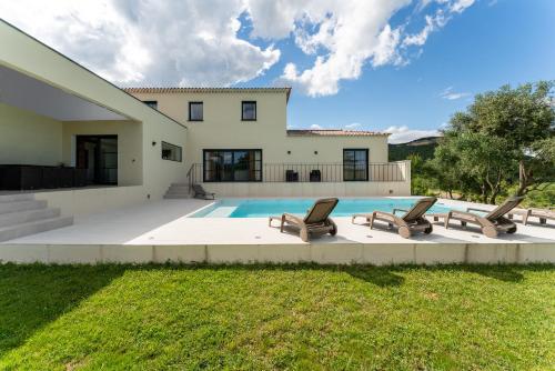 une maison avec une piscine et des chaises longues dans l'établissement Villa spacieuse et accueillante, à La Roque-sur-Cèze