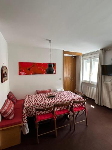 a dining room table with red chairs and a red painting at L'altra casa del Cervino in Breuil-Cervinia