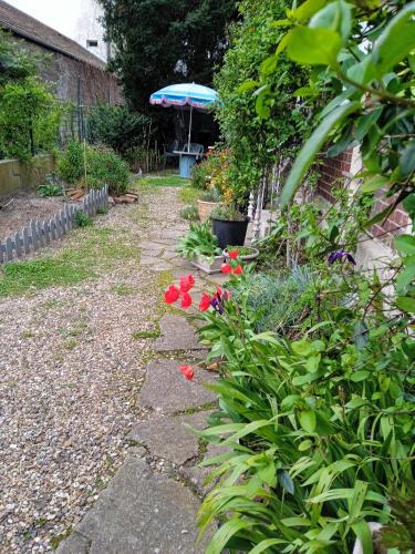 - un jardin avec un sentier de fleurs rouges et un parasol dans l'établissement Silver chambre, à Creil