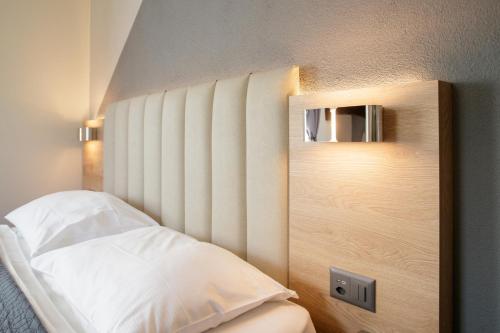 a bedroom with a white bed with a headboard at Albergo Mirador Ascona in Ascona