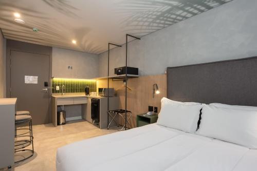 a bedroom with a white bed and a desk at Brava Mundo Hotel Boutique OFICIAL in Itajaí