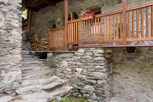 a stone house with a balcony and a stone wall at Les Cles - Genepy in Valsavarenche