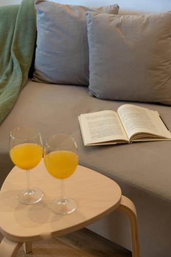 two glasses of orange juice and an open book on a table at Jardim do Morro Apartment By Porto Stories in Vila Nova de Gaia