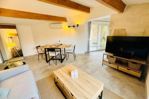 un salon avec une télévision et une table avec des chaises dans l'établissement Les Sarments charme de l'Ancien renové et au calme, à Mus