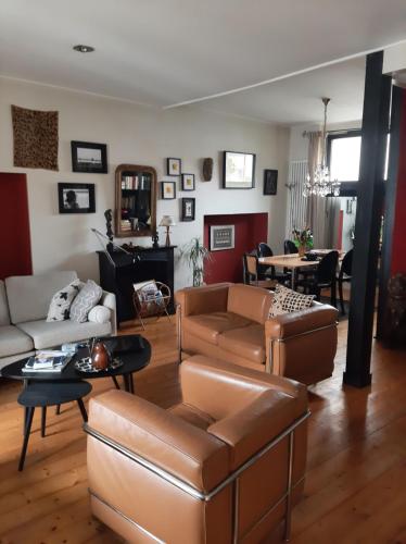 un salon avec des meubles en cuir marron et une salle à manger dans l'établissement Maison de charme, à La Rochelle