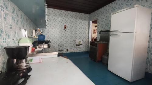 a small kitchen with a white refrigerator in a room at Moka Refúgium-Casa de praia aconchegante e espaçosa in Belém
