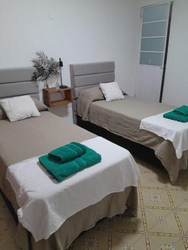 a room with two beds with green towels on them at CASA CENTRO Avenida Peron in La Rioja