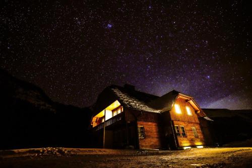 a house under a starry sky with lights on at Schaffergut Appartements in Donnersbachwald