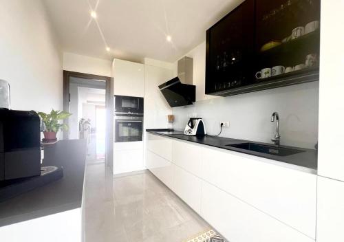 une cuisine avec des armoires blanches et des comptoirs noirs dans l'établissement Appt 2 bd-4 pers-Pool wifi Tennis Park-Sea view, à Cagnes-sur-Mer