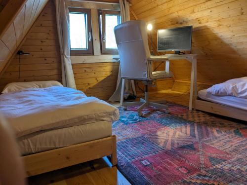 a bedroom with two beds and a desk with a television at Bohemian Paradise Chalet in Mladějov
