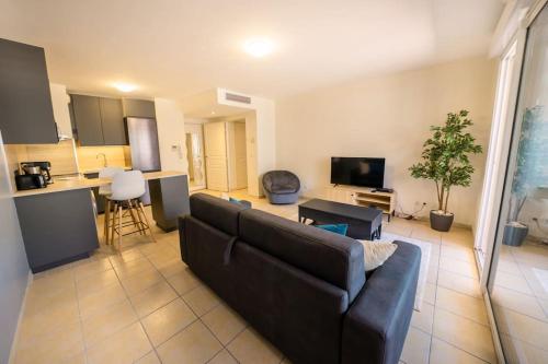 un salon avec un canapé et une cuisine dans l'établissement La terrasse d'Ernest T2 recent,Terrasse, Clim, CV, à Montpellier