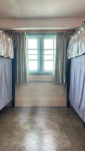 an empty room with two beds and a window at The Dreamcatcher Hostel Nathon SamuiSunset in Nathon