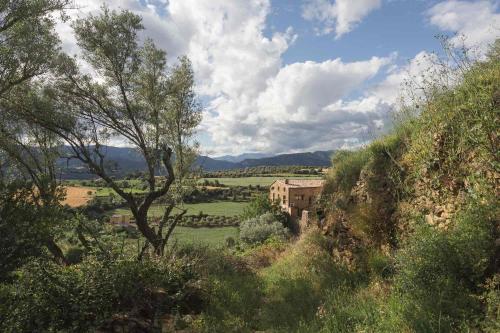 a view of a field with a building on a hill at Casa Jaumet: un lloc de pau on escoltar el silenci in Aramunt
