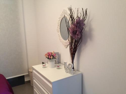 a dresser with a mirror and flowers on it at OasisBeach Penthousse la Zénia in Playas de Orihuela