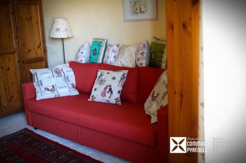 - un canapé rouge avec des oreillers dans l'établissement Chambre KIKO - Vue sur jardin et montagne AURIGNAC, à Aurignac