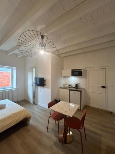 une chambre avec un lit, une table et des chaises dans l'établissement Le charme à la campagne dans toulousaine de 1900, à Bouloc