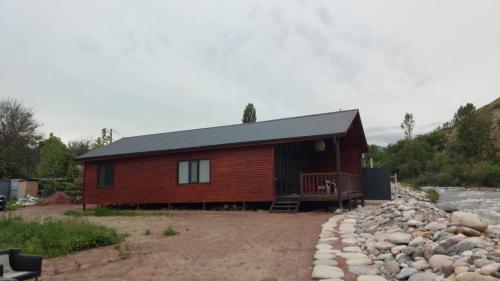 a small wooden cabin with a porch and rocks at Saisuu in Këk-Dzhar