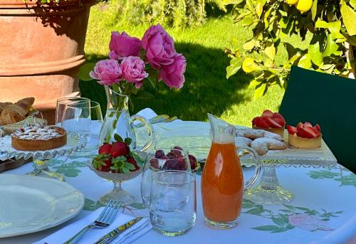 a table with pink roses and a vase of flowers at Relais La Magioca -Adults Only- in Negrar