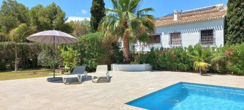 una piscina con due sedie e un ombrellone e una casa di Casa Belle a Jávea