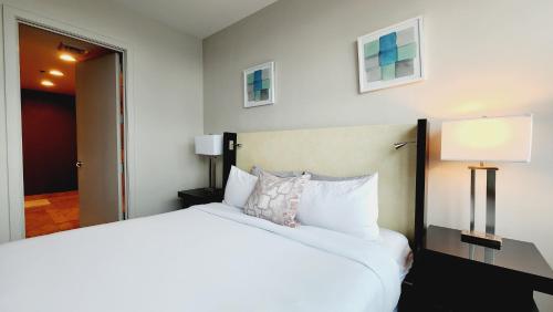 a bedroom with a large white bed and a lamp at Lux Aka Brickell Condo in Miami