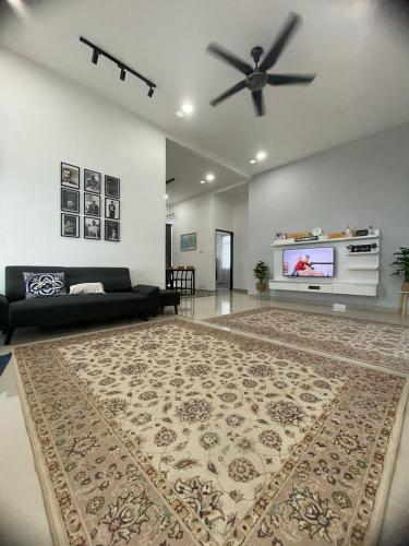 a living room with a black couch and a ceiling fan at Qayyum Homestay Pauh Lima,Bachok,Kelantan in Bachok