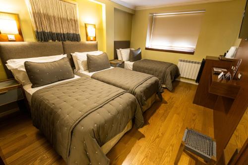 a hotel room with two beds and a window at Hotel Cap Polonio in Ushuaia