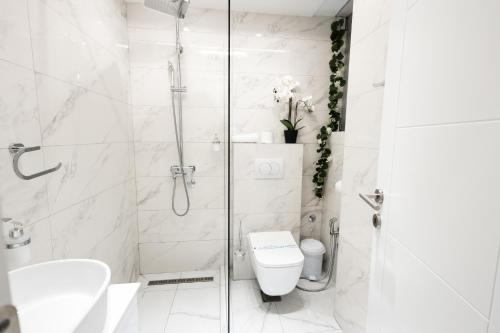 a white bathroom with a shower and a toilet at Garni Hotel Lotos in Niš