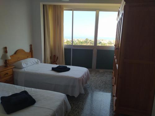 a hotel room with two beds and a large window at Casa El Barco in Torrox