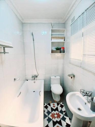 a white bathroom with a toilet and a sink at Zachi Apartments in Kitwe