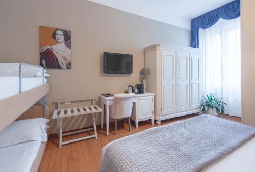 a bedroom with a bed and a desk and a tv at Hotel Ristorante Ala d'Oro in Lugo