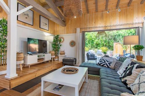 a living room with a blue couch and a tv at Magnifique Villa avec jacuzzi les 44Hectares in Cap-Ferret
