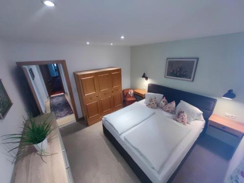 a bedroom with a white bed and a wooden cabinet at Haus Groder in Rauris