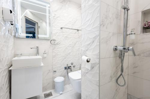 a bathroom with a shower and a toilet and a sink at Garni Hotel Lotos in Niš
