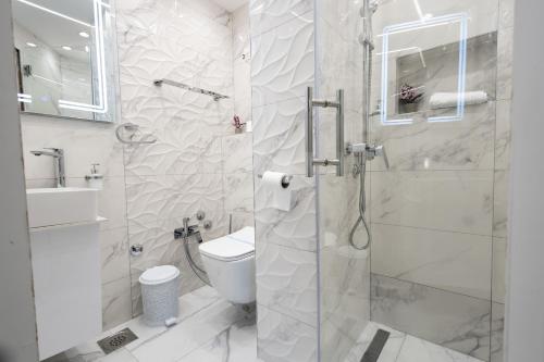 a white bathroom with a shower and a toilet at Garni Hotel Lotos in Niš