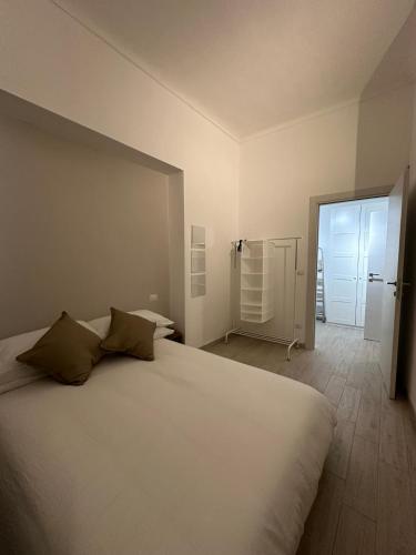 a bedroom with a large white bed and a door at L'Angolo Rosa in Casale Monferrato