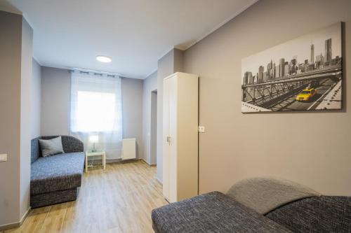 a living room with two chairs and a painting of a city at Riviéra Apartmanház in Siófok