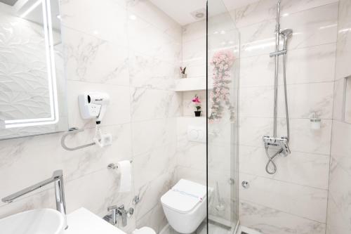 a white bathroom with a shower and a toilet at Garni Hotel Lotos in Niš