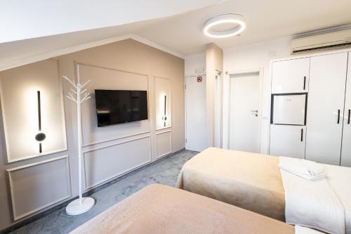 a bedroom with two beds and a flat screen tv at Garni Hotel Lotos in Niš