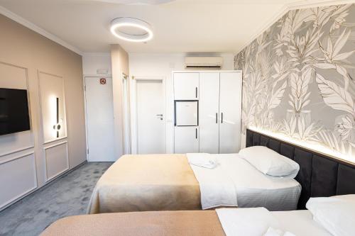 a hotel room with two beds and a flat screen tv at Garni Hotel Lotos in Niš