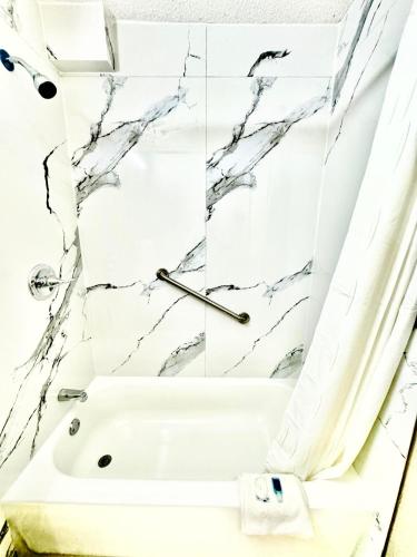 a bathroom with a white tub and marble walls at Rodeway Inn Expo Center in Spartanburg