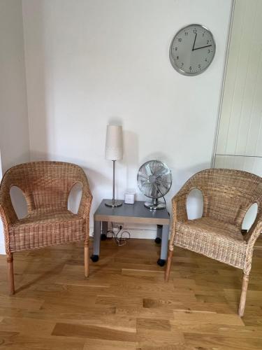 two chairs and a table with a clock on a wall at Björnnästet med havsutsikt innanför murarna in Visby
