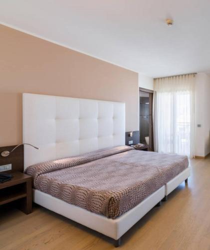 a bedroom with a large bed with a large headboard at Hotel Italy in Bibione