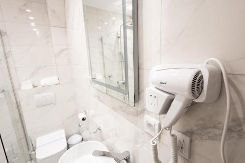 a white bathroom with a shower and a blow dryer at Garni Hotel Lotos in Niš