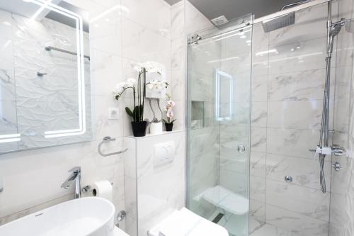a white bathroom with a shower and a sink at Garni Hotel Lotos in Niš