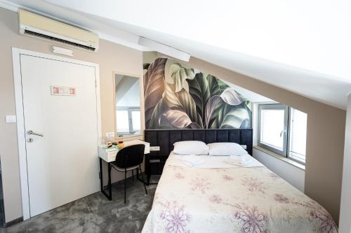 a small bedroom with a bed and a desk at Garni Hotel Lotos in Niš