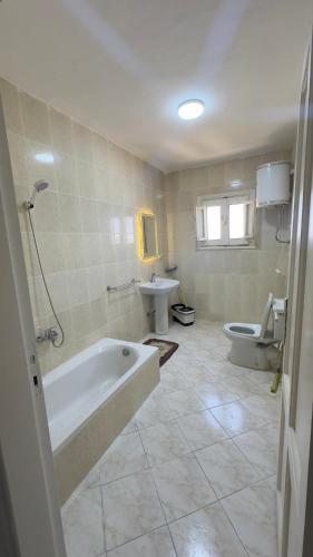 a bathroom with a tub and a toilet and a sink at Chalet 3 bedrooms Venus 2 Resort in Dawwār Ibrāhīm Abū Shunaywīr