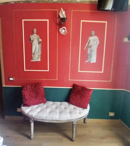 a room with two statues on the wall and a bench at Templum Iovis-Front of port in Civitavecchia