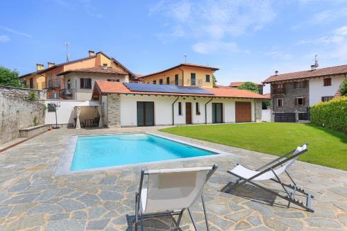 a swimming pool with two chairs and a house at Casa Noce with pool in Vezzo